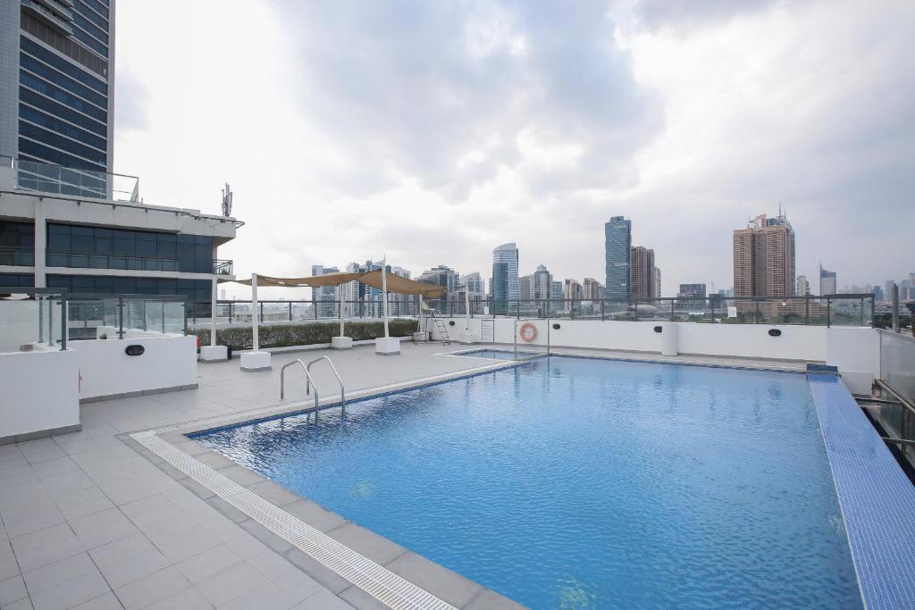 ein Pool auf dem Dach eines Gebäudes mit Skyline der Stadt in der Unterkunft J5 Tower - 1BR Apartment - Allsopp&Allsopp in Dubai