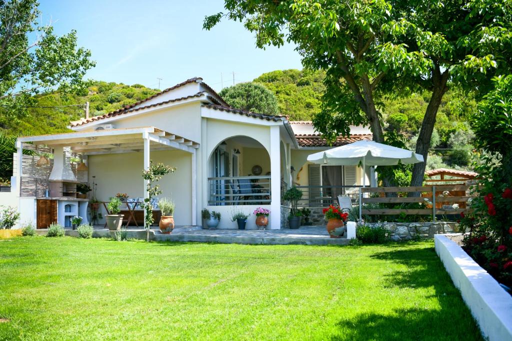 une petite maison blanche avec une cour verdoyante dans l'établissement Vague Summer House, à Skiathos Chora