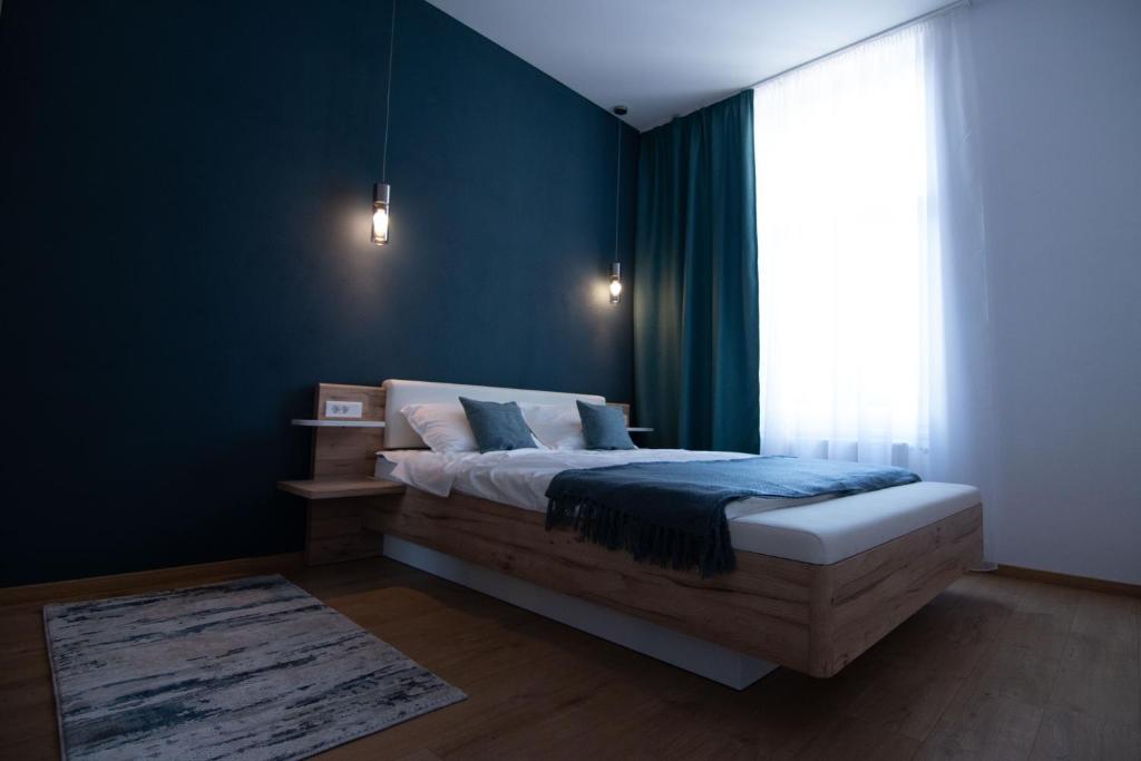 Schlafzimmer mit einem Bett mit blauen Wänden und einem Fenster in der Unterkunft Urban Six Apartments in Făgăraş