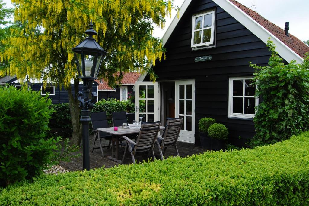 a black house with a table and chairs in the yard at d'Oude Herbergh, vakantiehuizen aan het water in Terherne