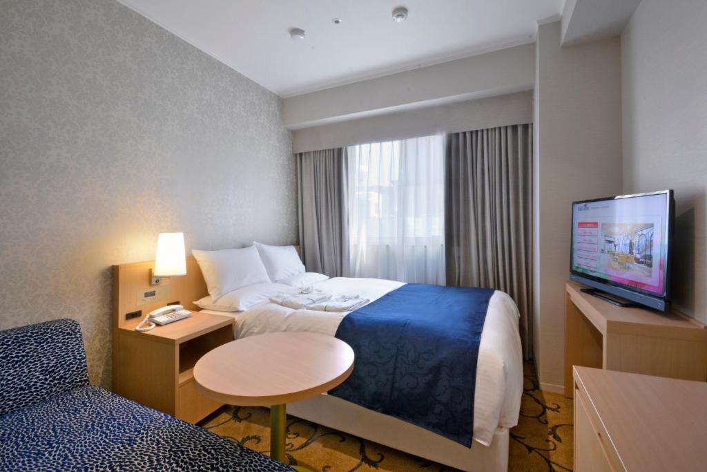 a hotel room with a bed and a tv at Hotel Rose Garden Shinjuku in Tokyo
