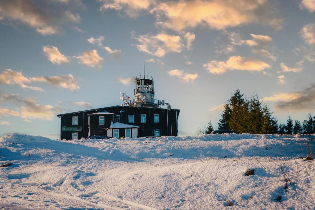 a lighthouse on top of a snow covered hill at Hotel Plesivec in Abertamy