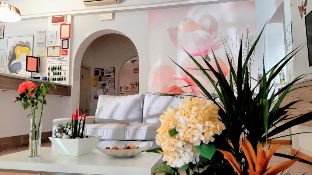 Hotel Amalfi في ريميني: غرفة معيشة مع أريكة وأزهار على طاولة