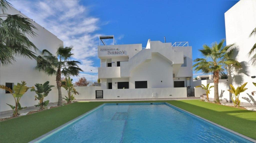 a villa with a swimming pool in front of a building at Luxe appartement met 2 badkamers / zee / zwembad in Lo Pagán
