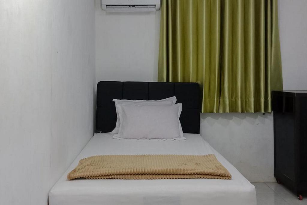 a bed with a white pillow and a green curtain at Citra Green House Syariah near Universitas Tulungagung in Tulungagung