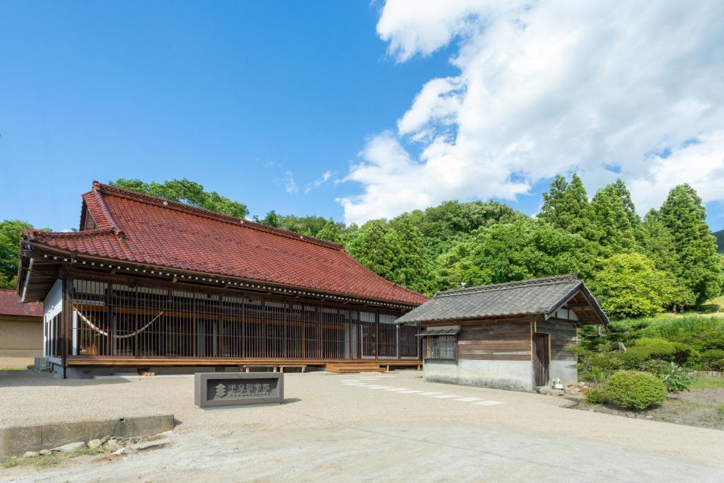 a building with a red roof with trees in the background at Hiraizumi Club -farm&resort- Vacation Stay in Hiraizumi