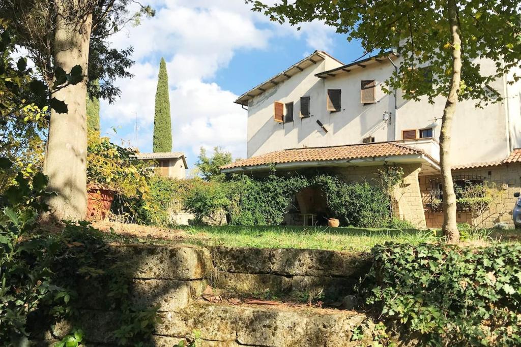 a white house with a tower in the background at Villa in Toscana a due passi da Saturnia in San Giovanni delle Contee