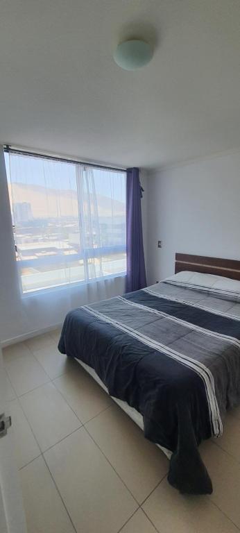 - une chambre avec un lit et une grande fenêtre dans l'établissement Edificio Bulnes - Cavancha, à Iquique