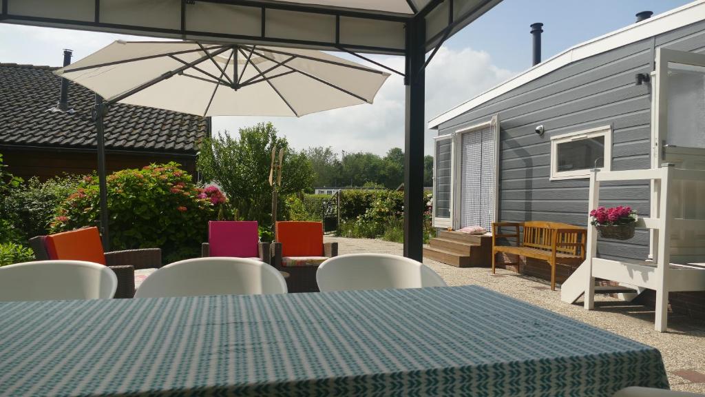 un patio con mesa, sillas y sombrilla en Het ScheldeChalet, en Baarland