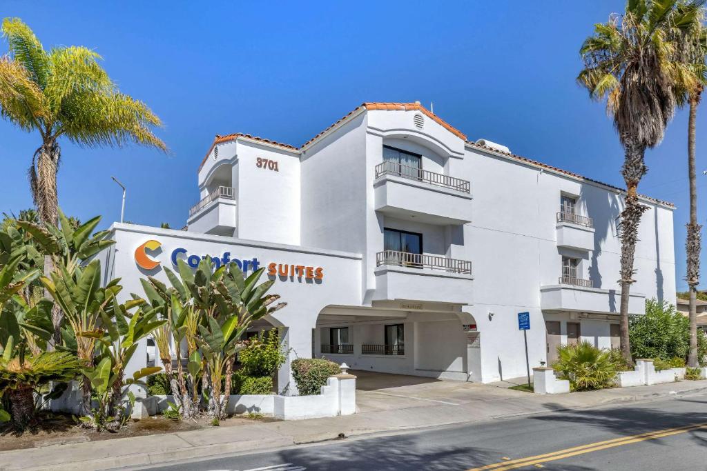 a white building with palm trees in front of it at Comfort Suites San Clemente Beach in San Clemente