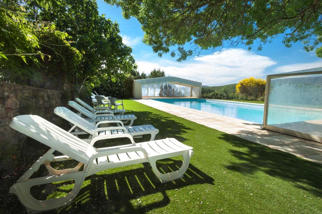 a row of lounge chairs sitting next to a swimming pool at Domaine Les Terres de Saint-Hilaire in Ollières
