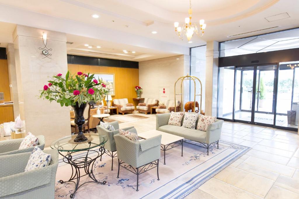a lobby with couches and chairs and a table with flowers at Hotel Rose Garden Shinjuku in Tokyo