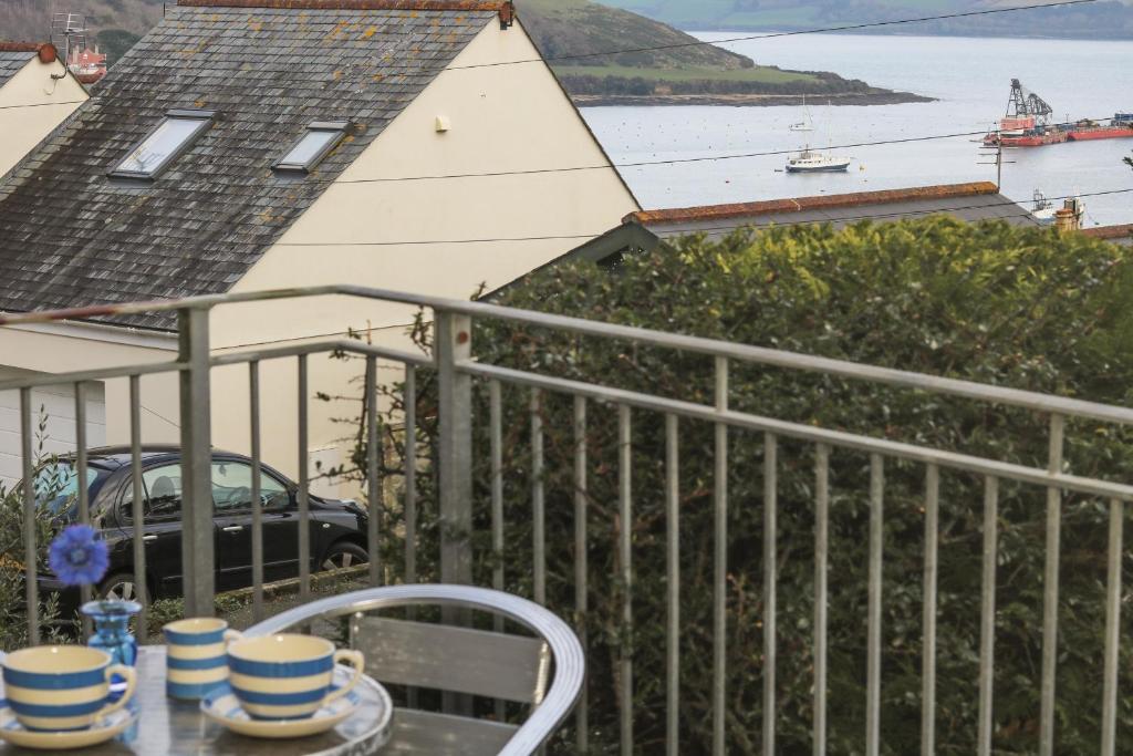 a balcony with a table and a view of the water at Hawkins Haven in Falmouth