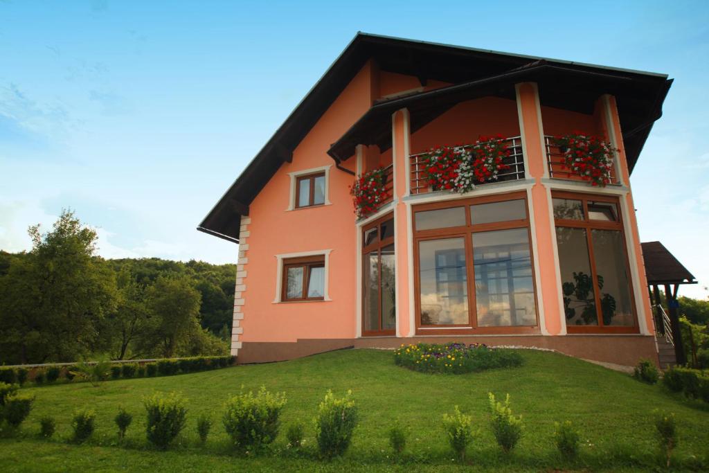 a house with a balcony on a green lawn at Rooms Marković in Otočac