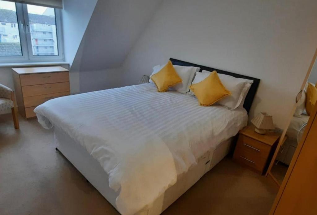 a bedroom with a white bed with yellow pillows at Apartment D505 in Northampton