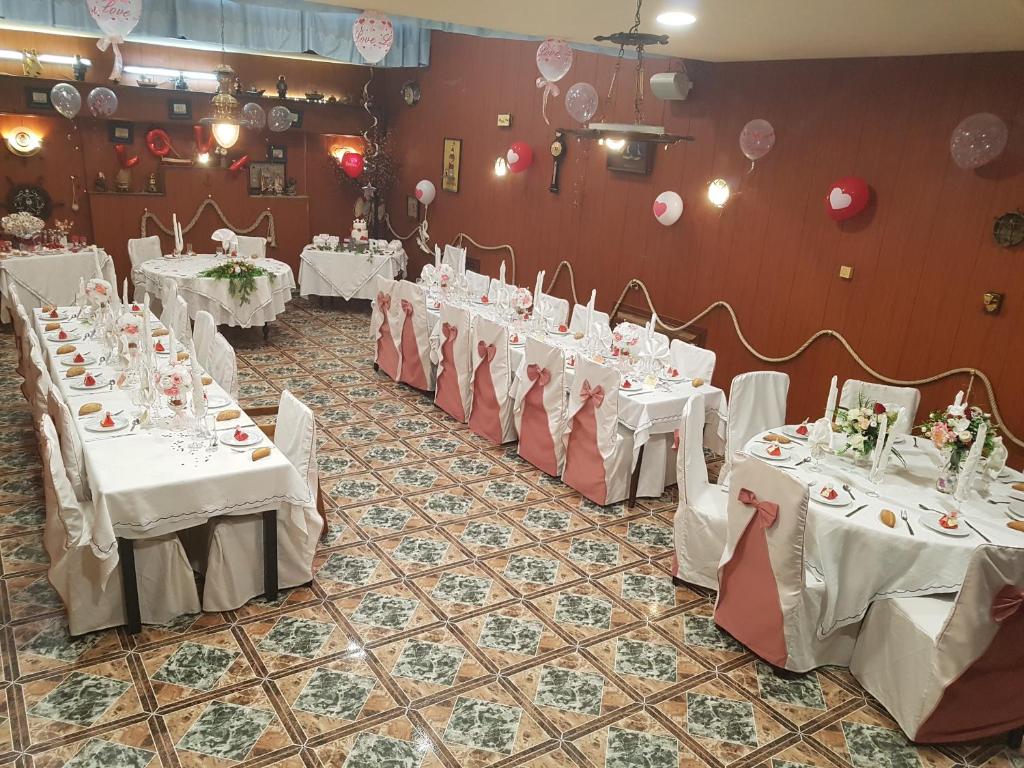 a row of tables in a room with white table settings at Hostal Milenium in Els Monjos