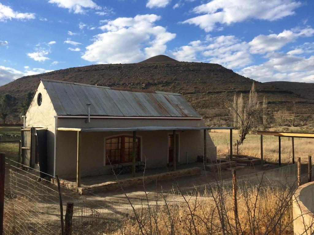 a small white building with a mountain in the background at Die Kapokbosskuur in Nieu-Bethesda