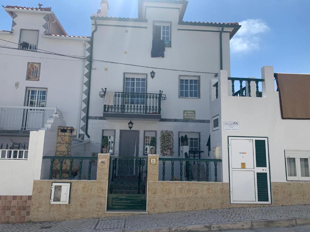 um grande edifício branco com um portão em frente em Moradia Ricardo - Nazaré em Nazaré