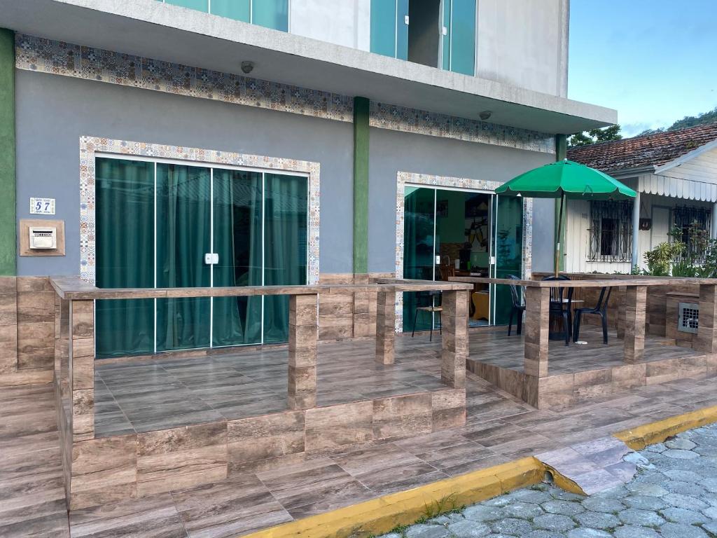 een houten terras met een tafel en een parasol bij Kitnet Praia do Trapiche in Penha