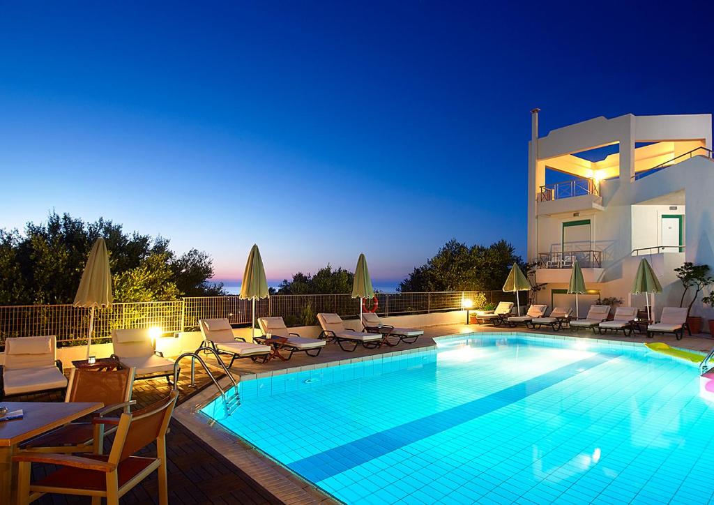 a large swimming pool with chairs and a house at Bella Vista Hotel "by Checkin" in Hersonissos