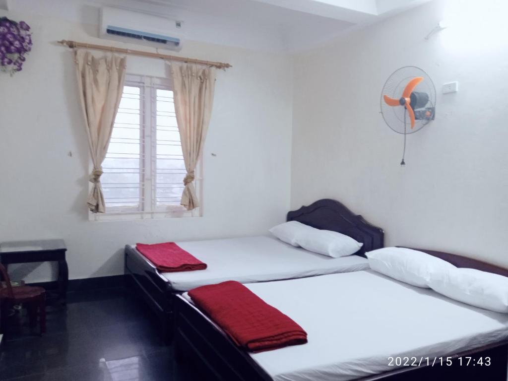 two twin beds in a room with a window at Nhà Nghỉ Hải Yến in Tinh Xa