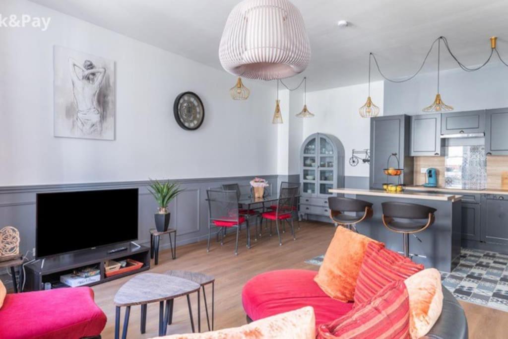 a living room with a red couch and a kitchen at Cauquilha SPACIEUX APPARTEMENT BOURGEOIS EN CENTRE VILLE in Béziers