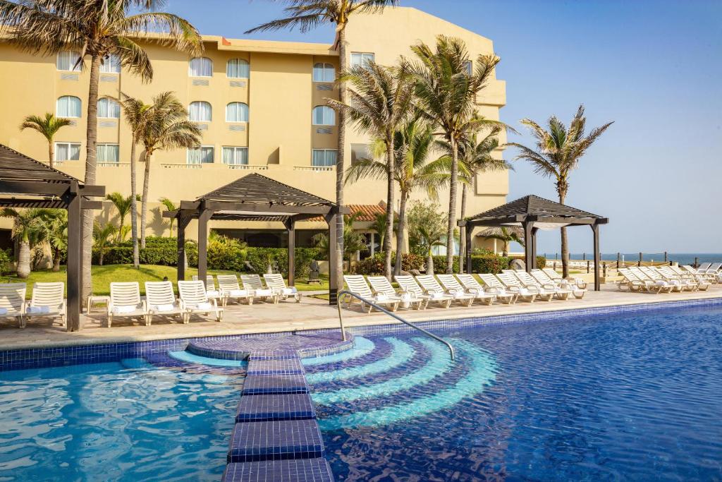 a swimming pool with chairs and a hotel at Fiesta Inn Veracruz Boca Del Rio in Veracruz