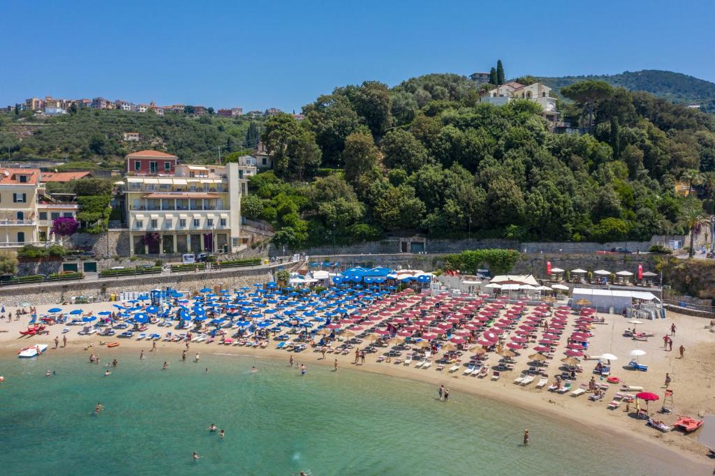 a beach with a bunch of umbrellas and people in the water at Hotel Venere Azzurra in Lerici