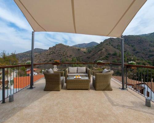 a patio with chairs and a table with mountains in the background at Del Conte in Kalopanayiotis
