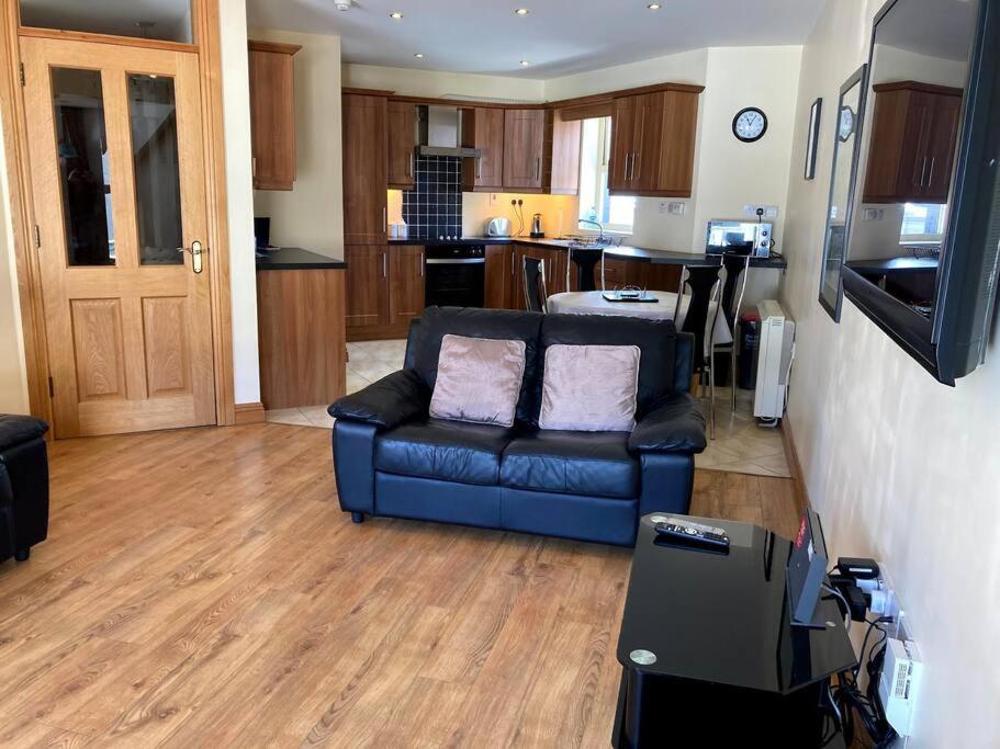 uma sala de estar com um sofá azul e uma cozinha em Charlies Lane Apartment em Donegal