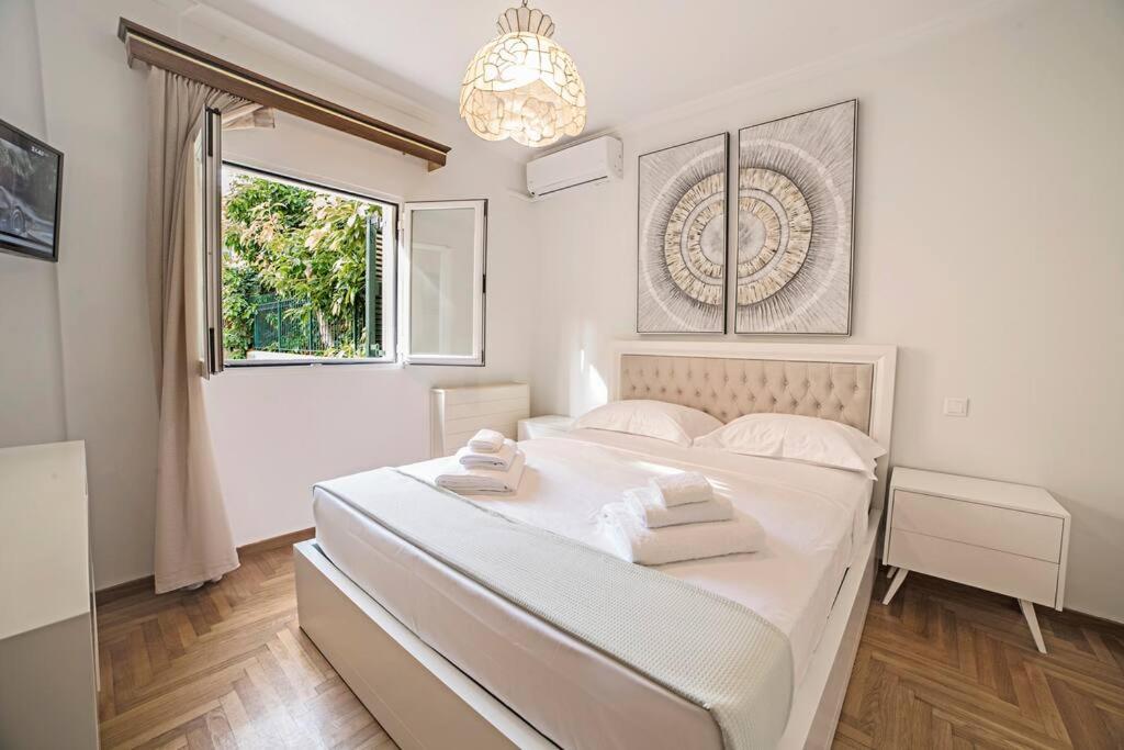 a white bedroom with a bed and a window at Casa Tua @ Tennis Corfu Club! in Ágios Rókkos