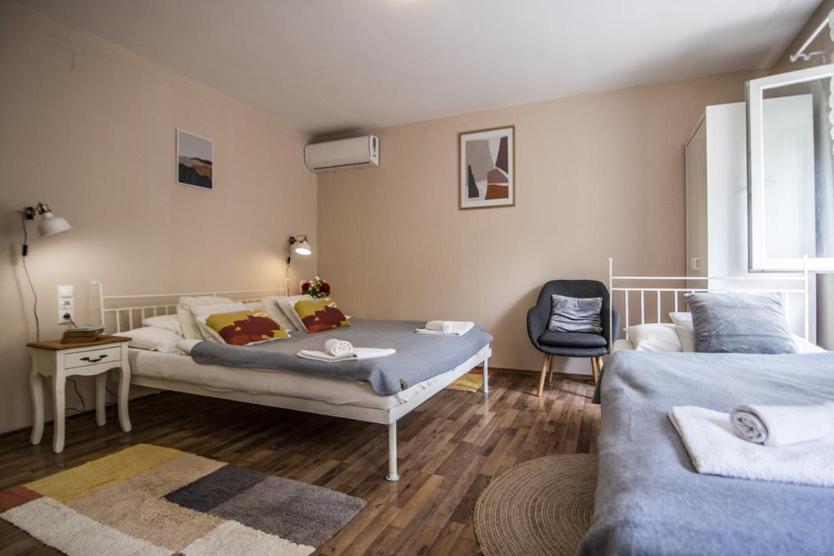 een slaapkamer met 2 bedden en een stoel. bij Vági Apartment in Sárvár