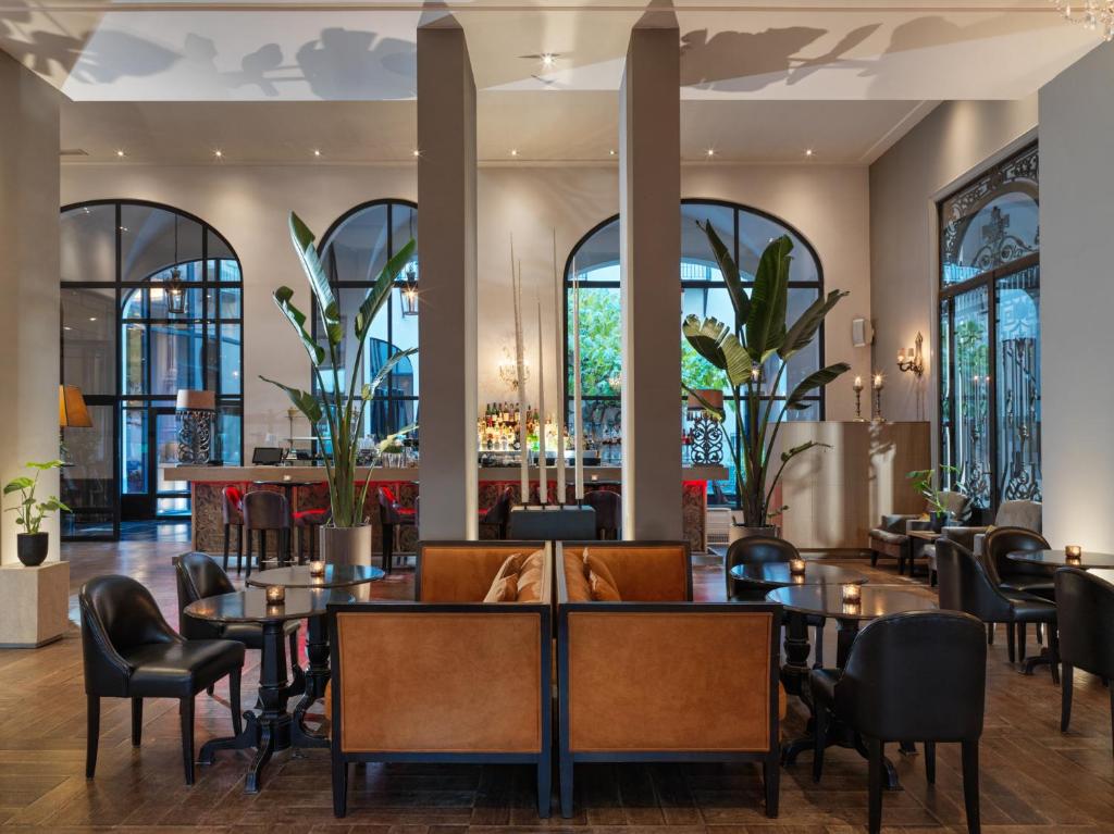 um restaurante com mesas e cadeiras e um bar em The Dominican, Brussels, a Member of Design Hotels em Bruxelas