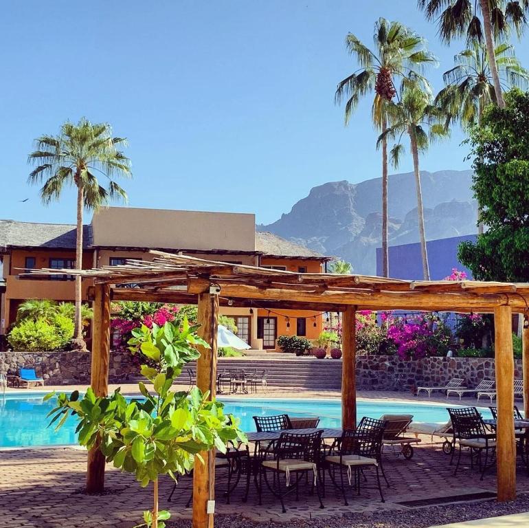 a resort with a pool and chairs and palm trees at Tripui Hotel in Puerto Escondido