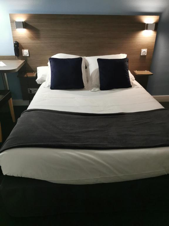 a large bed with black and white sheets and pillows at Hotel au Moyne De Saire in Réville