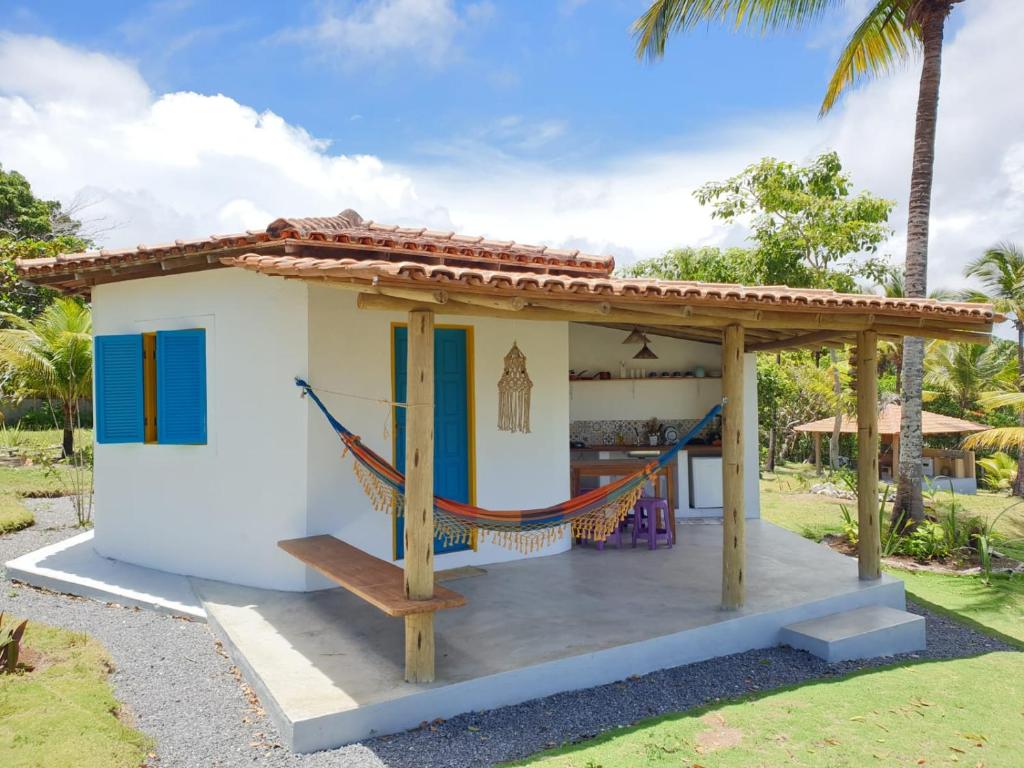 a small white house with a porch and a hammock at Canto do Mar - Chalés com vista pro Mar - Cumuruxatiba in Cumuruxatiba