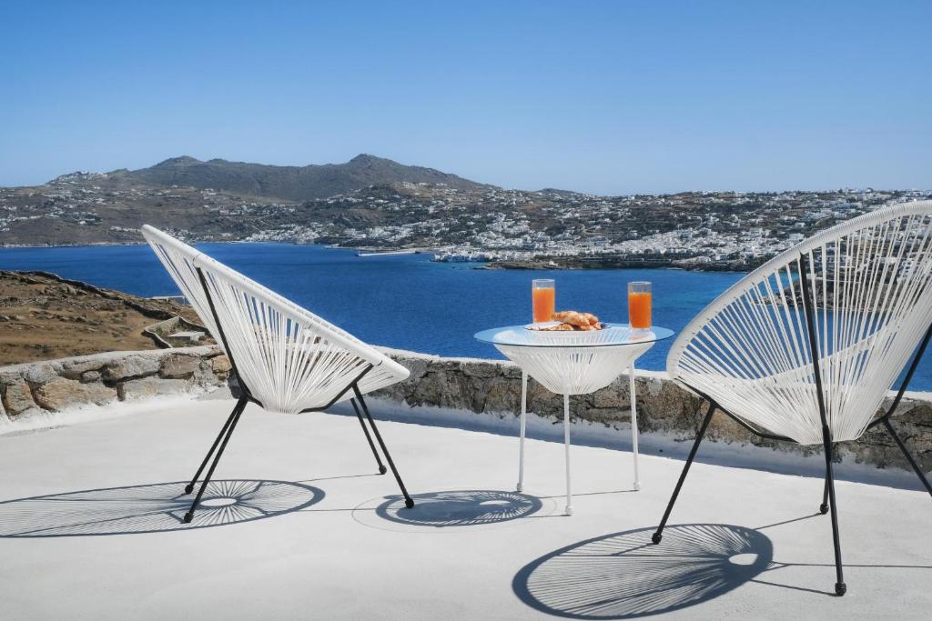 duas cadeiras e uma mesa com vista para o oceano em Vista Infinita em Agios Ioannis