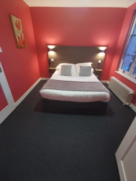 a bedroom with a large bed with red walls at Hotel au Moyne De Saire in Réville