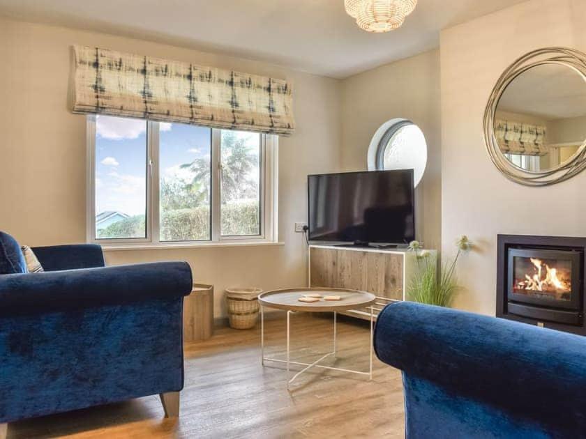 a living room with two blue couches and a tv at Nicosia House with sea views. in Westward Ho