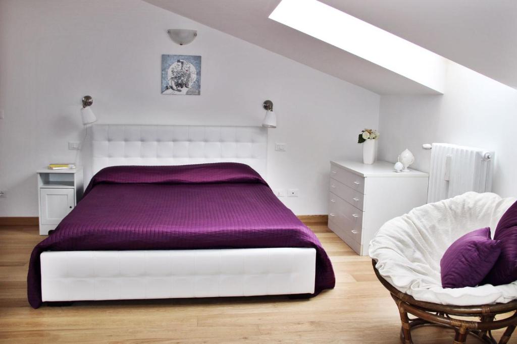 Dormitorio blanco con cama morada y silla en Realkasa Lovin House, en Bolonia
