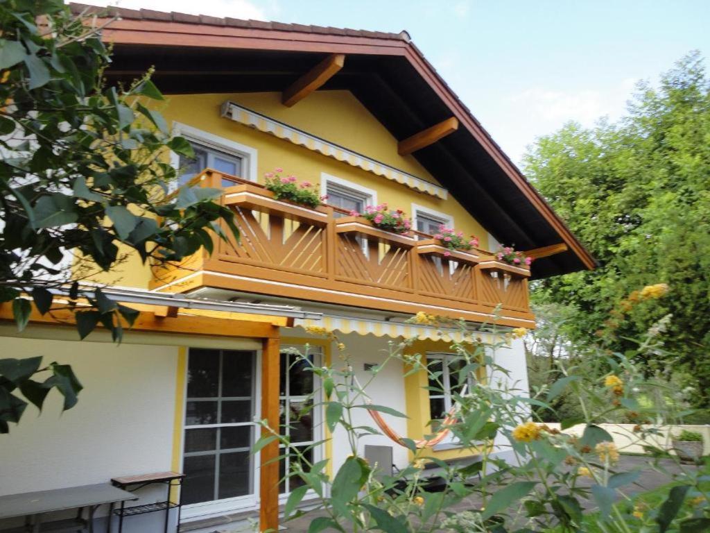 a yellow house with a balcony with flowers on it at Haus Fiedler in Piding