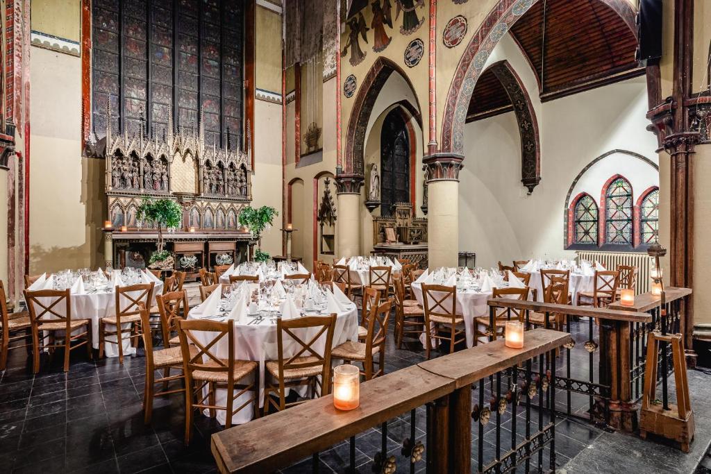 a dining room with tables and chairs in a church at Hotel Monasterium PoortAckere Ghent in Ghent