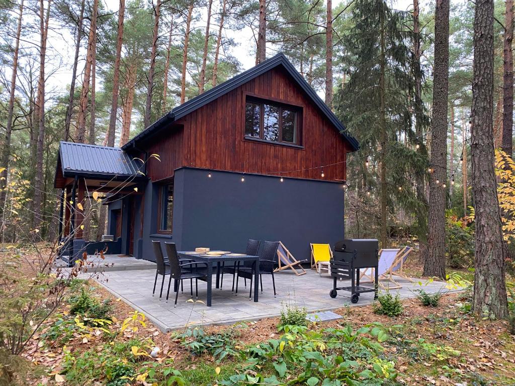 a small cabin with a table and chairs in the woods at Domek z SAUNĄ na leśnej działce w Wildze in Wilga
