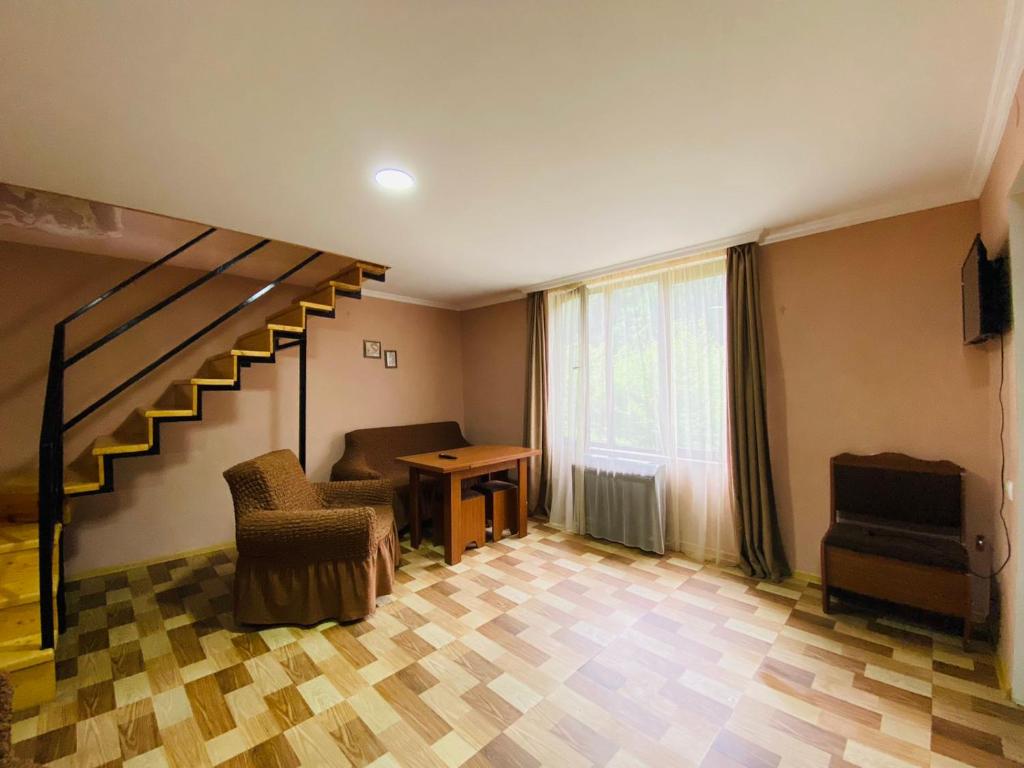 uma sala de estar com uma escada e uma mesa e cadeiras em Likani house em Borjomi
