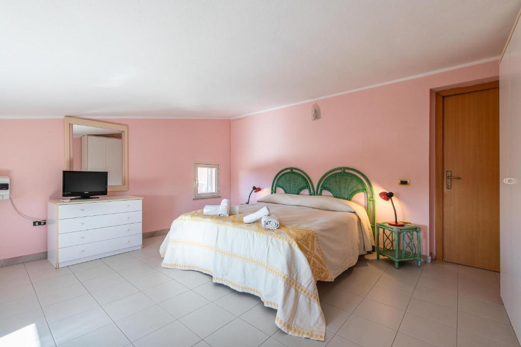 - une chambre rose avec un lit et une télévision dans l'établissement Villa erica appartamento Loredana, à Villa San Pietro