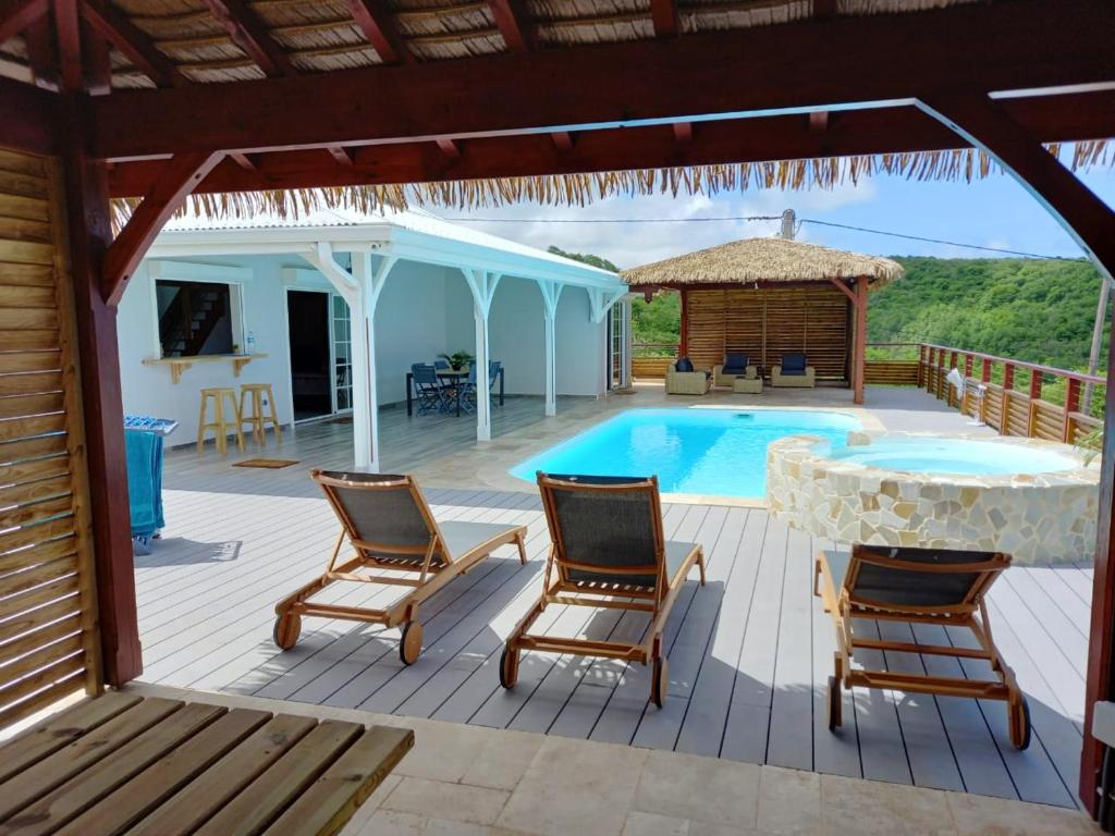 a patio with a table and chairs and a swimming pool at Villa de 3 chambres avec vue sur la mer piscine privee et jacuzzi a Le Marin in Le Marin