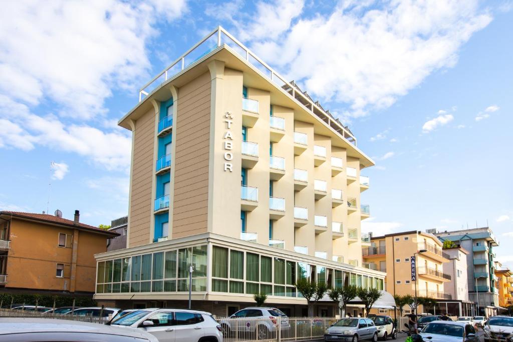 un edificio di un hotel con auto parcheggiate di fronte di Hotel Tabor a Rimini