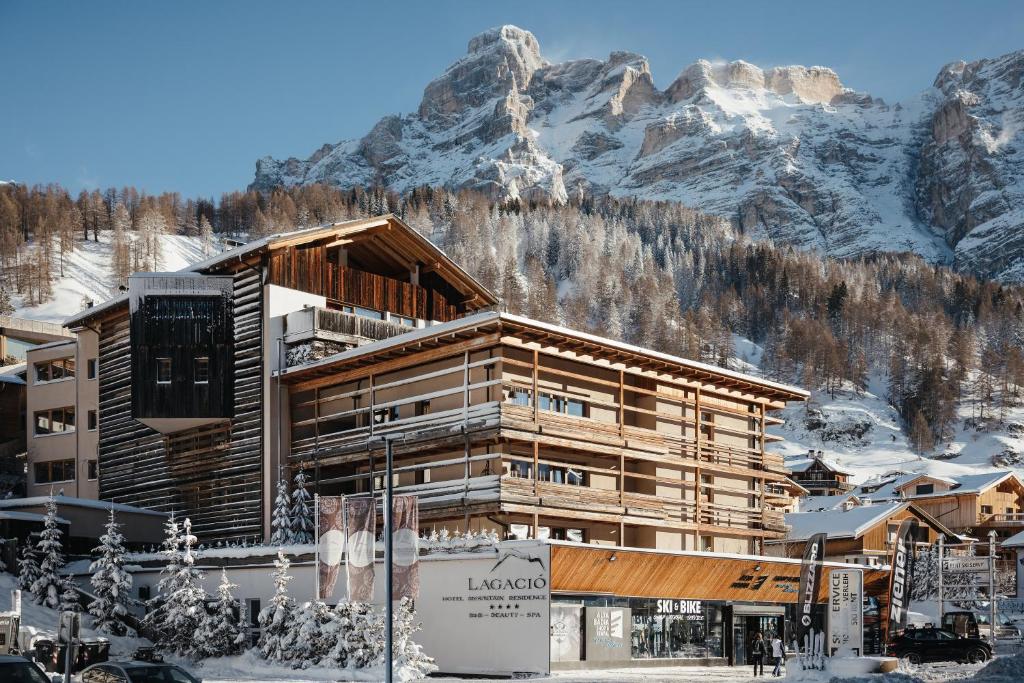 a ski lodge with a mountain in the background at Lagació Hotel Mountain Residence in San Cassiano
