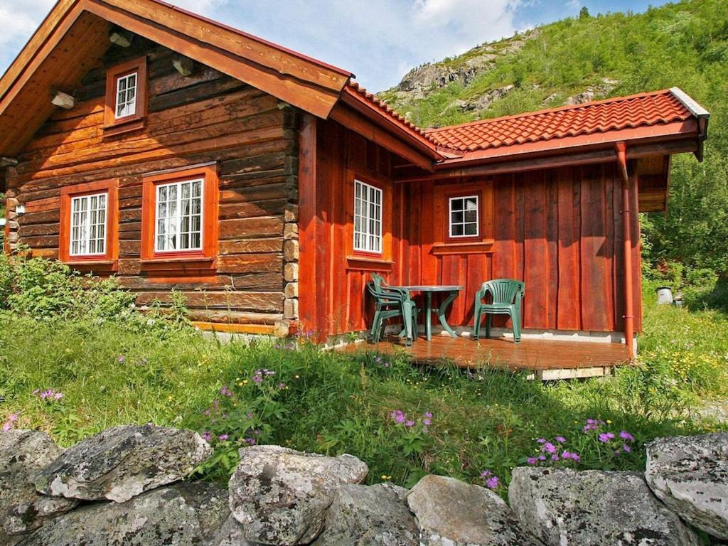 uma cabana de madeira com uma mesa e cadeiras à sua frente em Holiday home Hemsedal II em Hemsedal