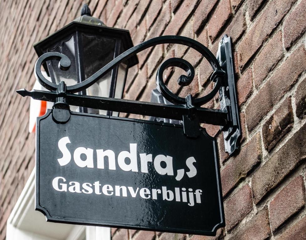 un cartel pegado a una pared de ladrillo con un letrero de la calle en Sandra’s Gastenverblijf, en Oostvoorne